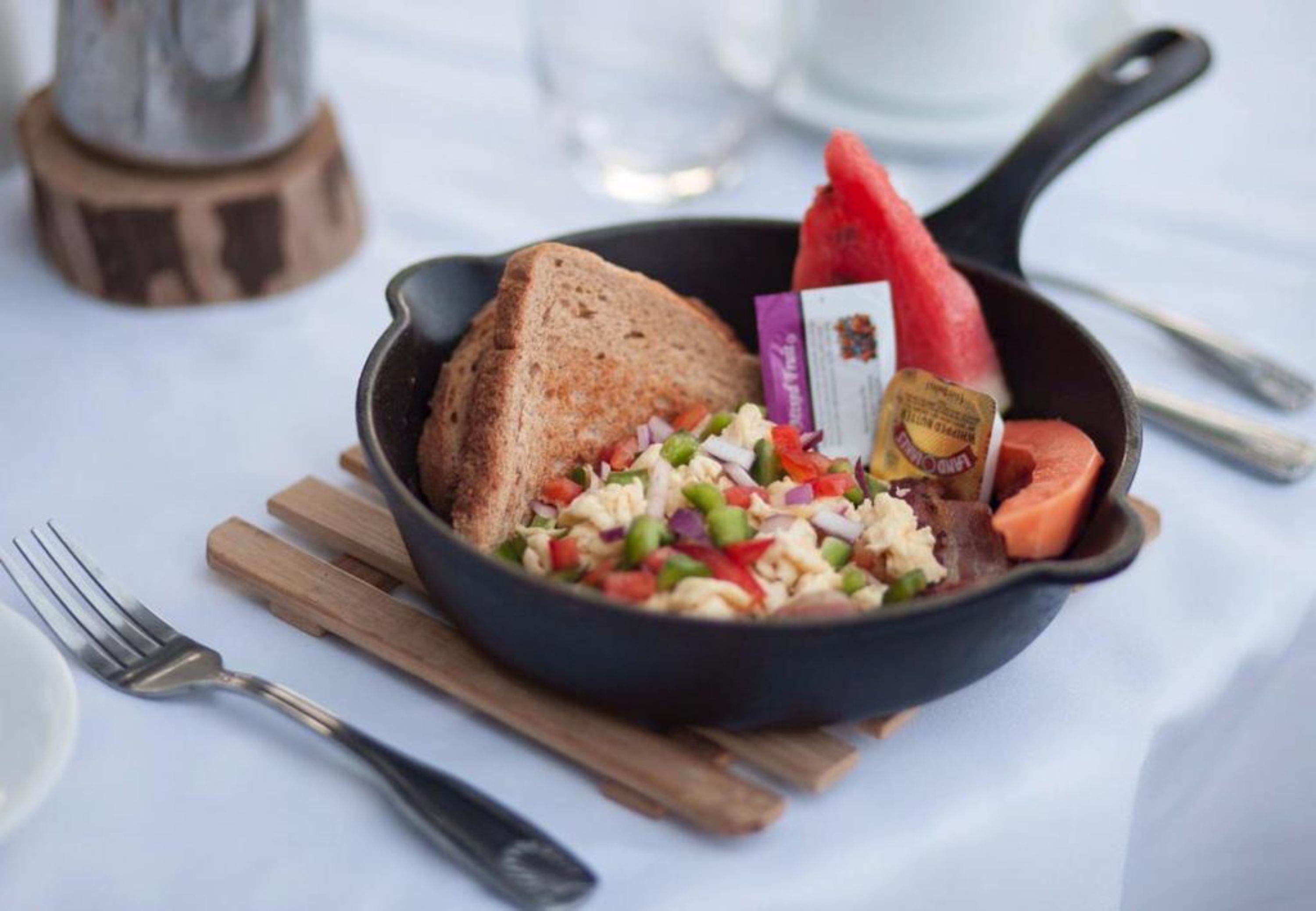 A breakfast plate with toast, scrambled eggs, and a slice of watermelon.