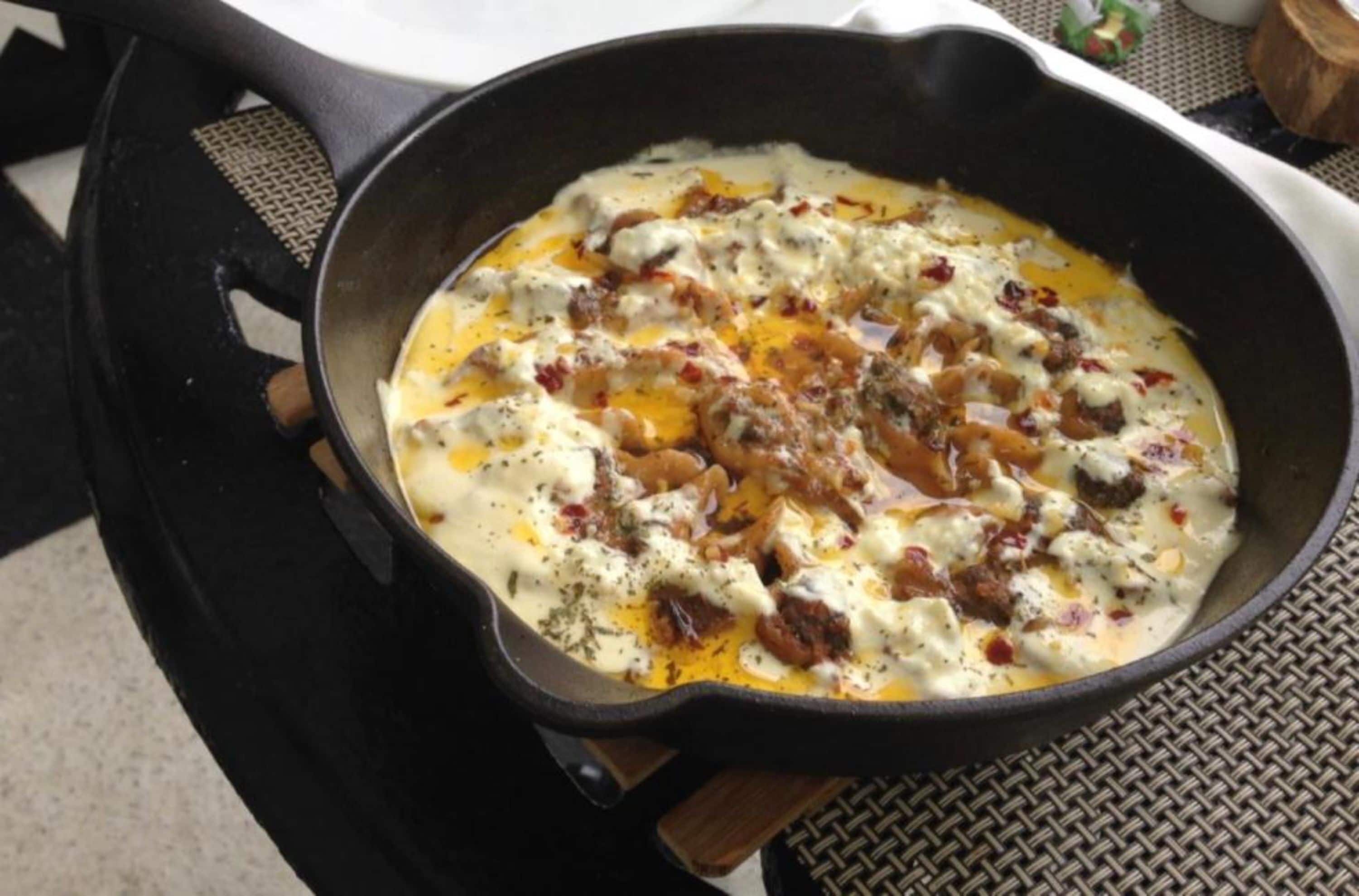 A skillet with a dish containing meat and sauce.