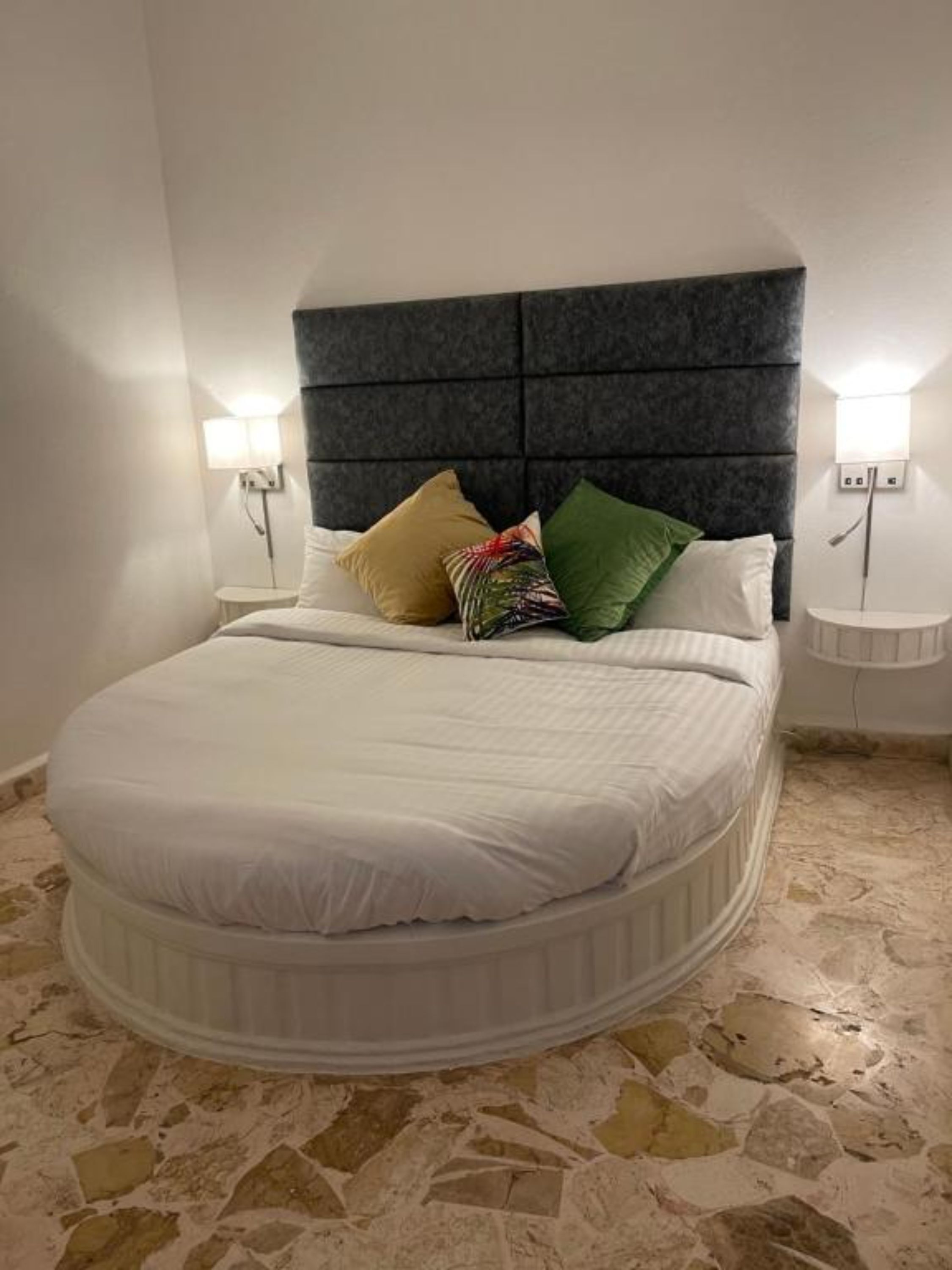 A bed with a headboard, two bedside tables, and a stone floor.