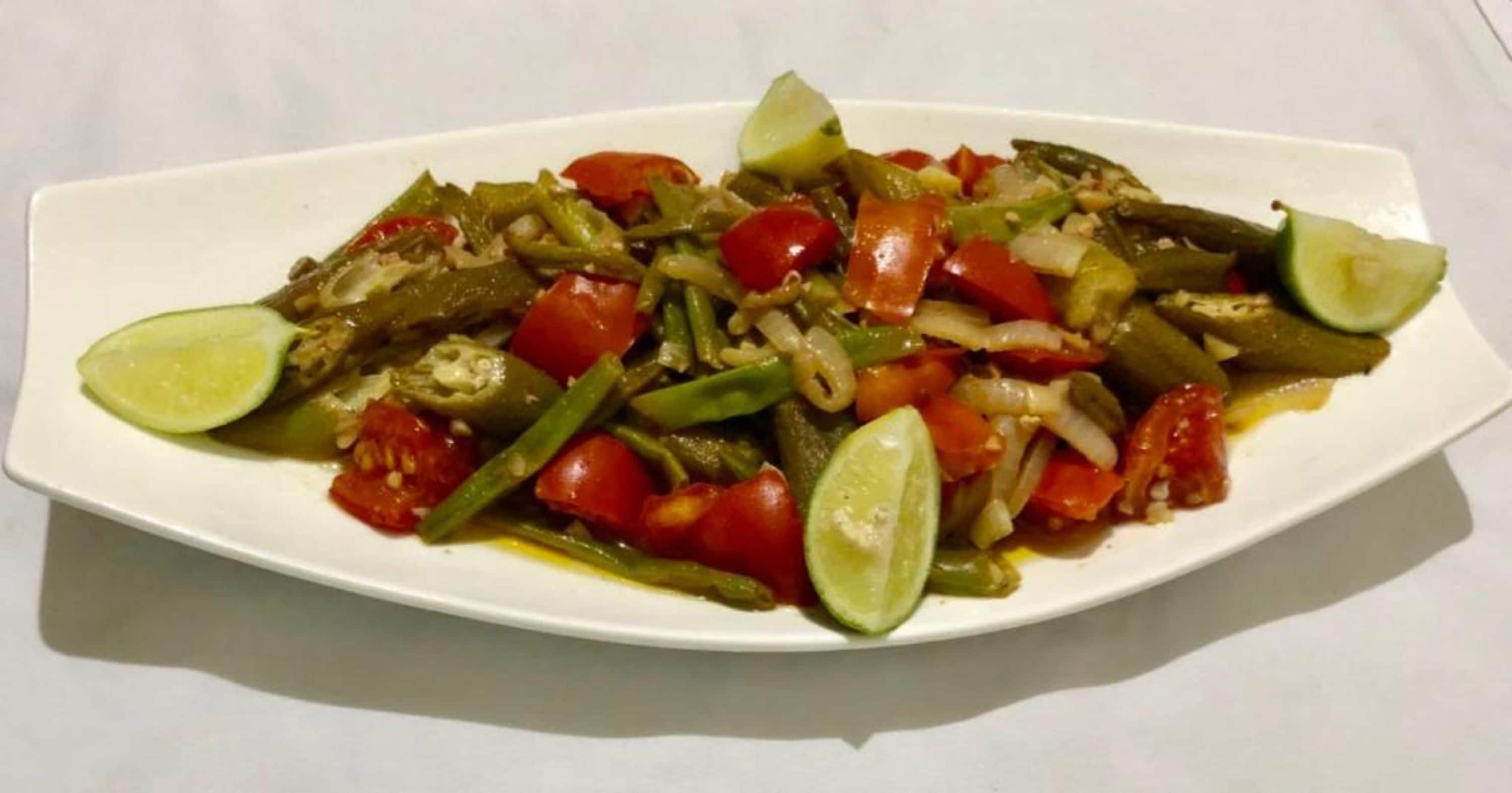 A plate of stir-fried vegetables with lime wedges.
