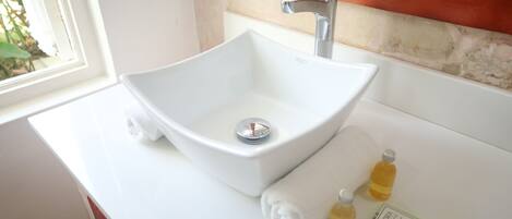 A white bathroom sink with a modern faucet, a towel, and two bottles of lotion on the countertop.