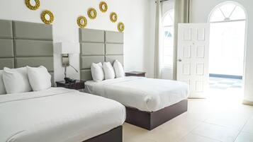 Habitación de hotel con dos camas, una mesita de noche con lámpara, aire acondicionado instalado en la pared y decoración circular en la pared.
