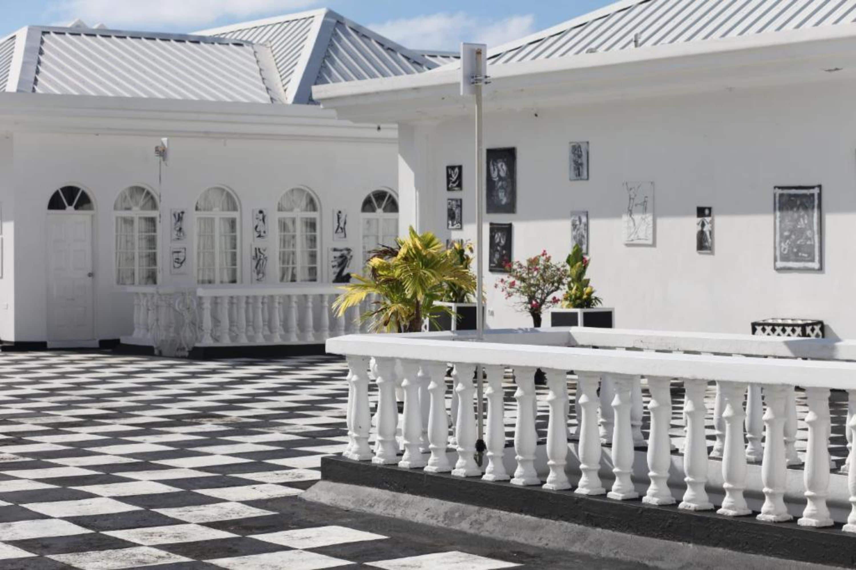 A white building with a checkered floor, arched windows, and a white balcony railing.