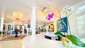 A spacious lobby with a high ceiling, a chandelier, and a large painting. - Jamaica Palace Hotel (Port Antonio)