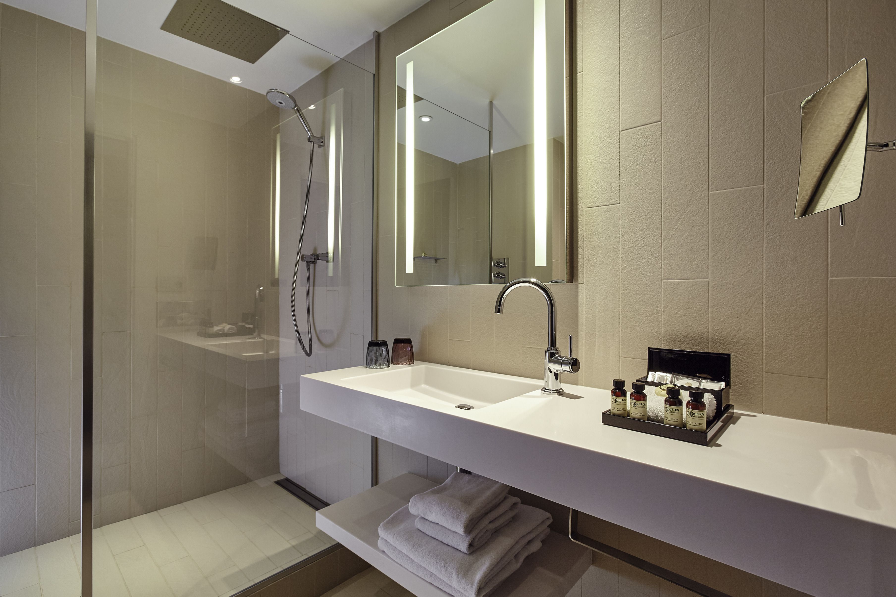 A modern bathroom with a large mirror, a sink, and a shower.