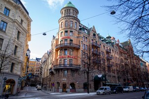 Un hotel histórico con una característica torre en esquina, varios balcones y un estilo arquitectónico europeo clásico.