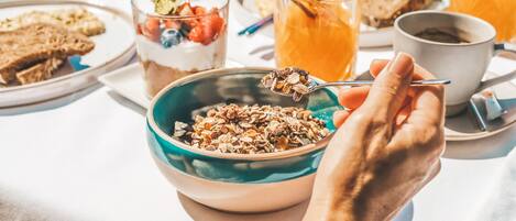 A breakfast setting with a bowl of granola, toast, and a glass of orange juice.