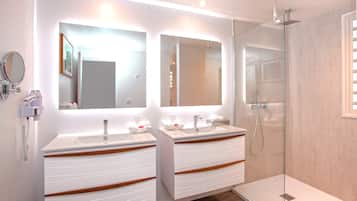 Une salle de bain moderne avec deux lavabos, une douche en verre et un miroir au-dessus de chaque lavabo.
