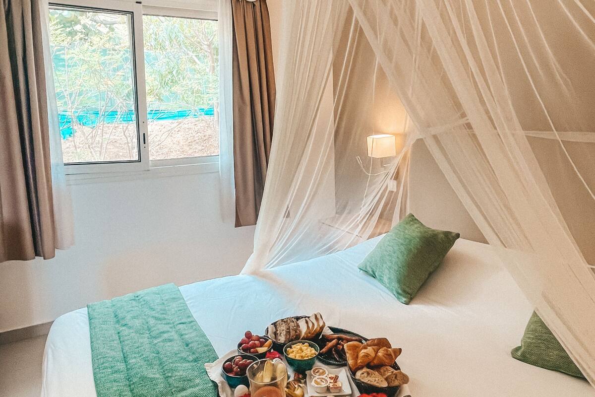 A bed with a canopy, a tray of food, and a window with curtains.