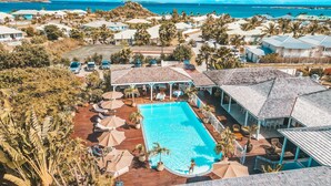 A resort with a swimming pool, lounge chairs, and a view of the ocean. - Hotel La Plantation (Orient Bay)