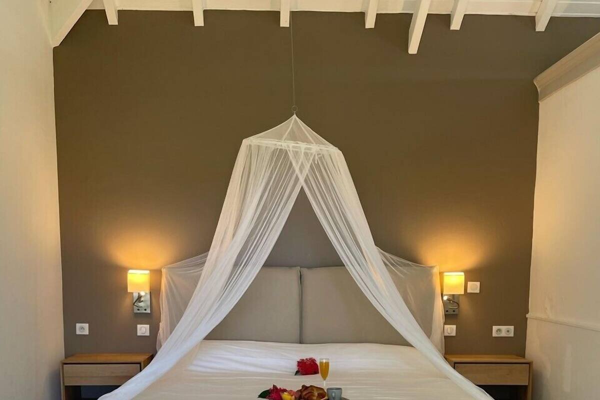 A large bed with a canopy, two bedside tables with lamps, and a tray with breakfast items.