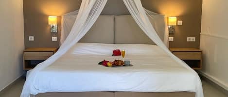 Un grand lit à baldaquin, deux tables de chevet avec des lampes et un plateau contenant des articles pour le petit-déjeuner.