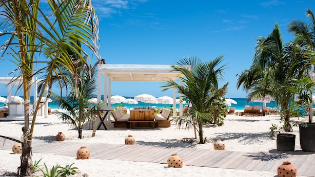 A beachside resort with wooden deck seating, palm trees, and beach umbrellas. - Hotel La Plantation (Orient Bay)