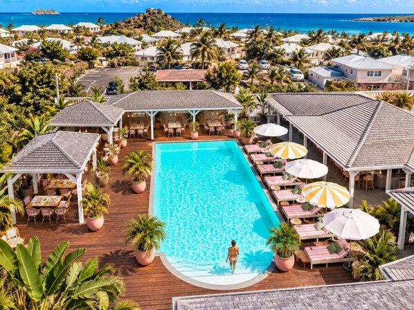 A resort with a swimming pool, outdoor seating, and a view of the ocean. - Hotel La Plantation (Orient Bay)