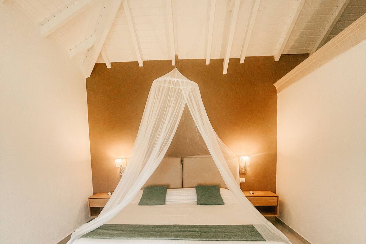 A bedroom with a canopy bed, two bedside tables, and a nightstand.