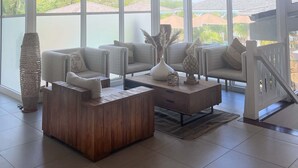 A spacious room with large windows, wicker pendant lights, and a wooden coffee table. - Hotel La Plantation (Orient Bay)