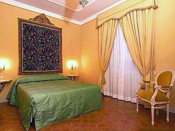 A hotel room with a bed, a chair, a painting, and curtains. - Castello Orsini Hotel (Nerola)