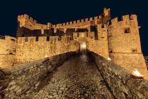 A stone castle with a central arched entrance and a cobblestone pathway leading to it. - Castello Orsini Hotel (Nerola)