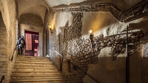 A stone staircase with a metal handrail, a red door at the top, and a wall with a decorative metal pattern. - Castello Orsini Hotel (Nerola)
