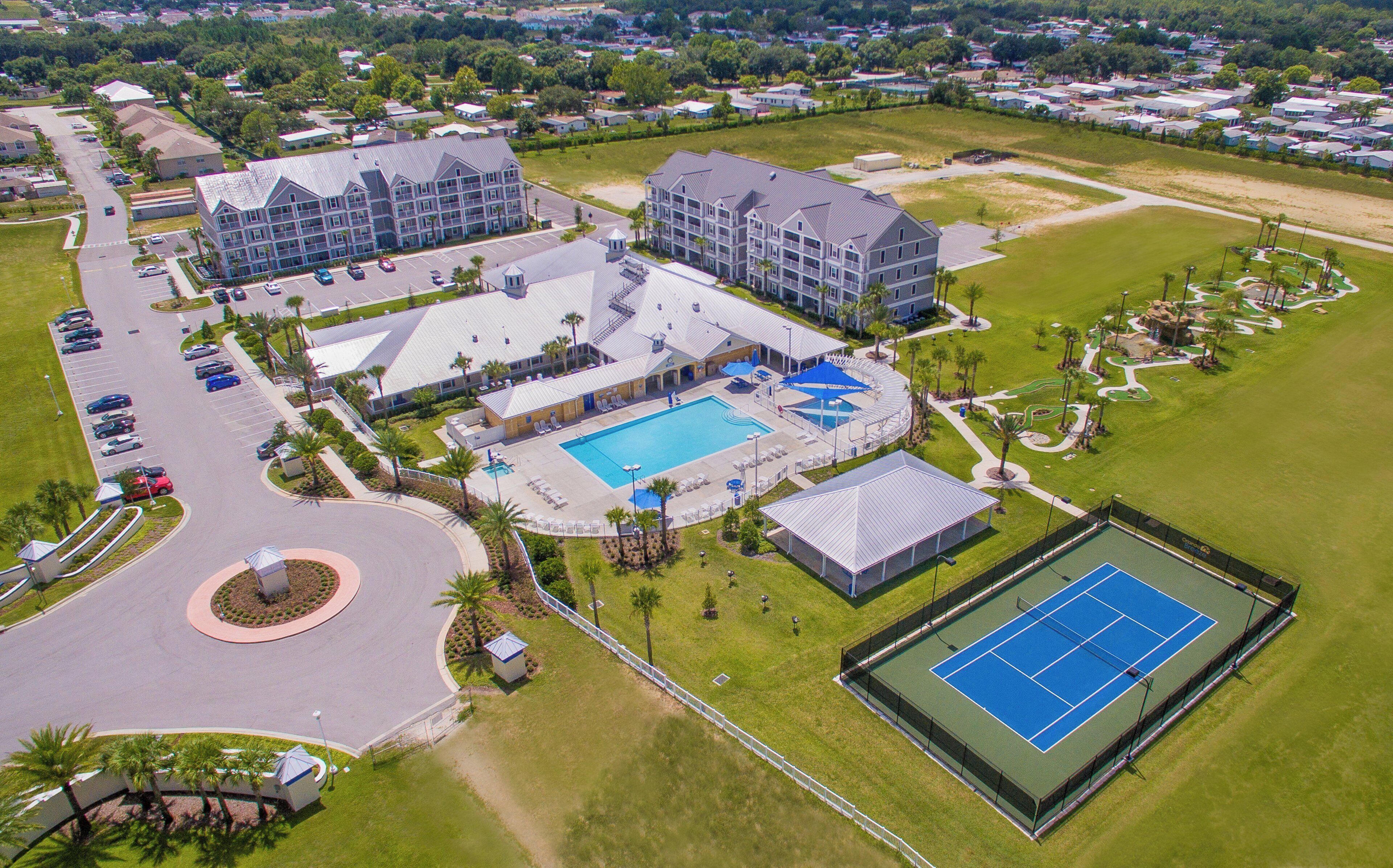 A multi-story hotel with a swimming pool, tennis court, and landscaped grounds.