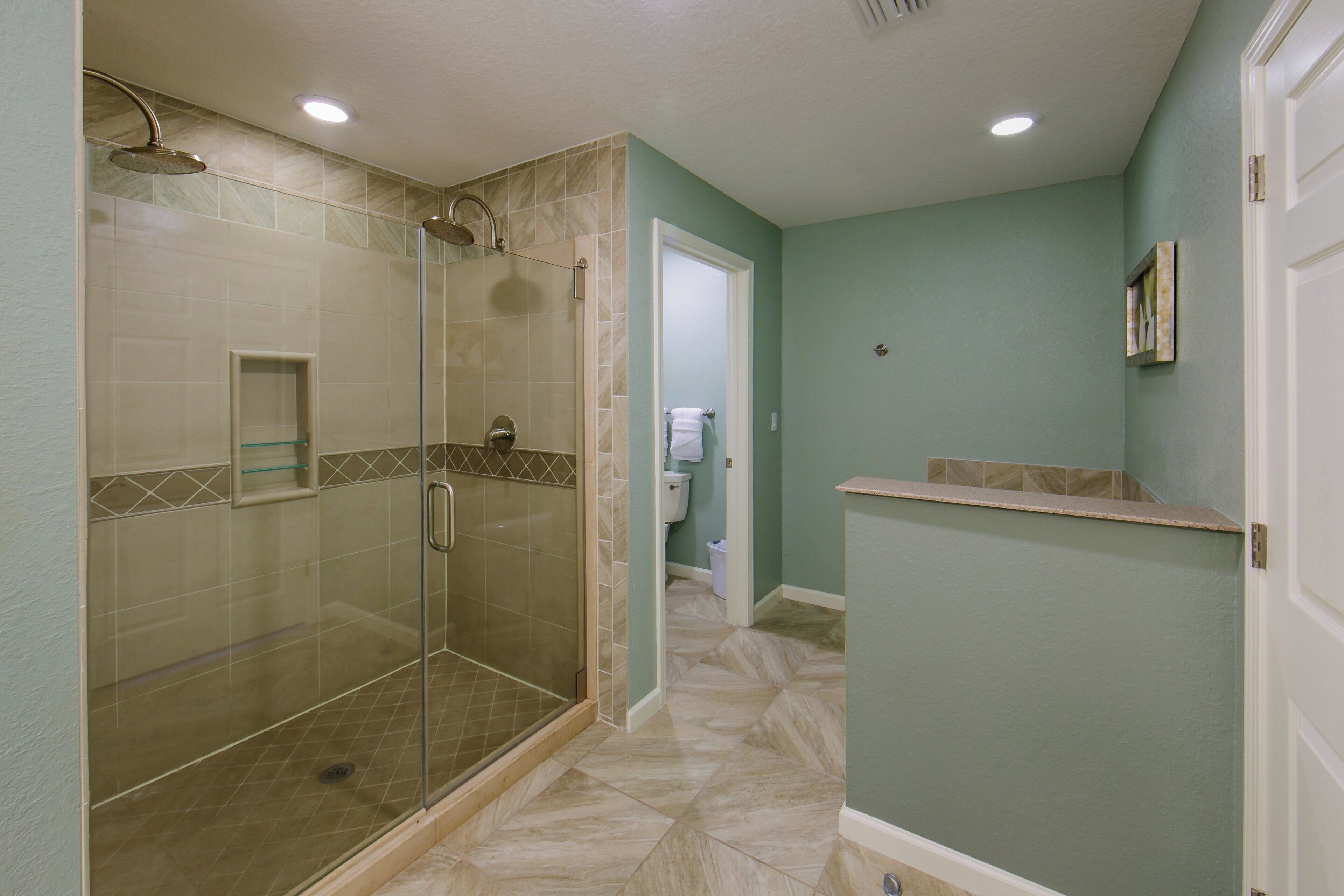A bathroom with a glass-enclosed shower, a toilet, and a sink.