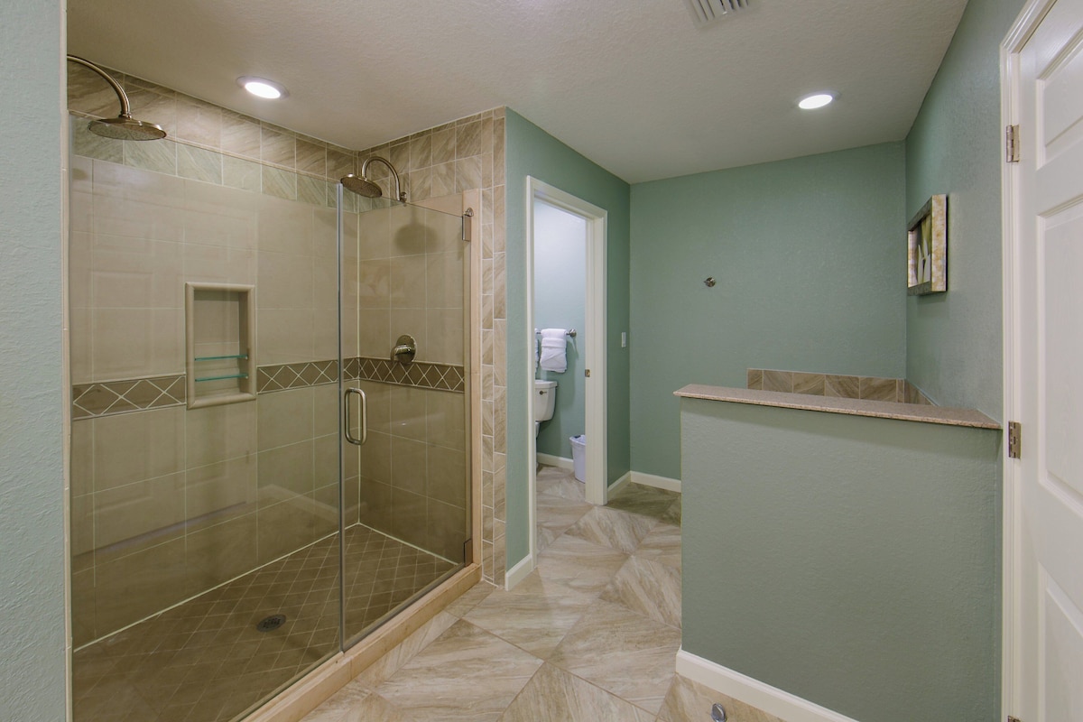 A bathroom with a glass-enclosed shower, a toilet, and a sink.