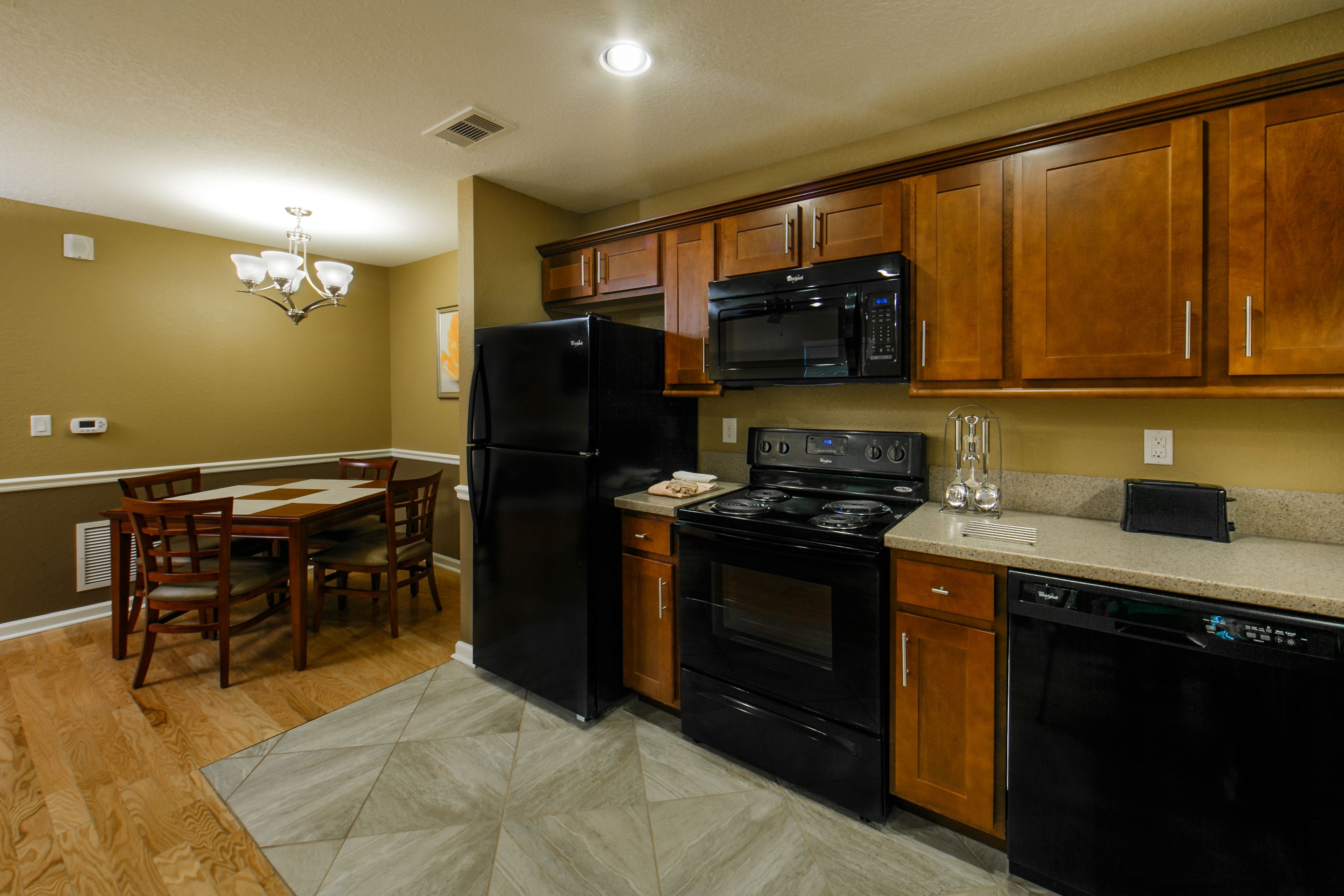 A kitchen with wooden cabinets, a black refrigerator, a microwave, a stove, and a dishwasher.