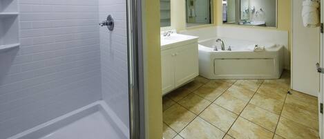 Un baño con ducha, lavamanos y bañera, con sanitarios blancos y pared amarilla.