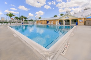 A swimming pool with a lifeguard tower, lounge chairs, and a covered area with a clock.