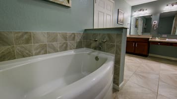 Un baño con bañera, lavabo y espejo.