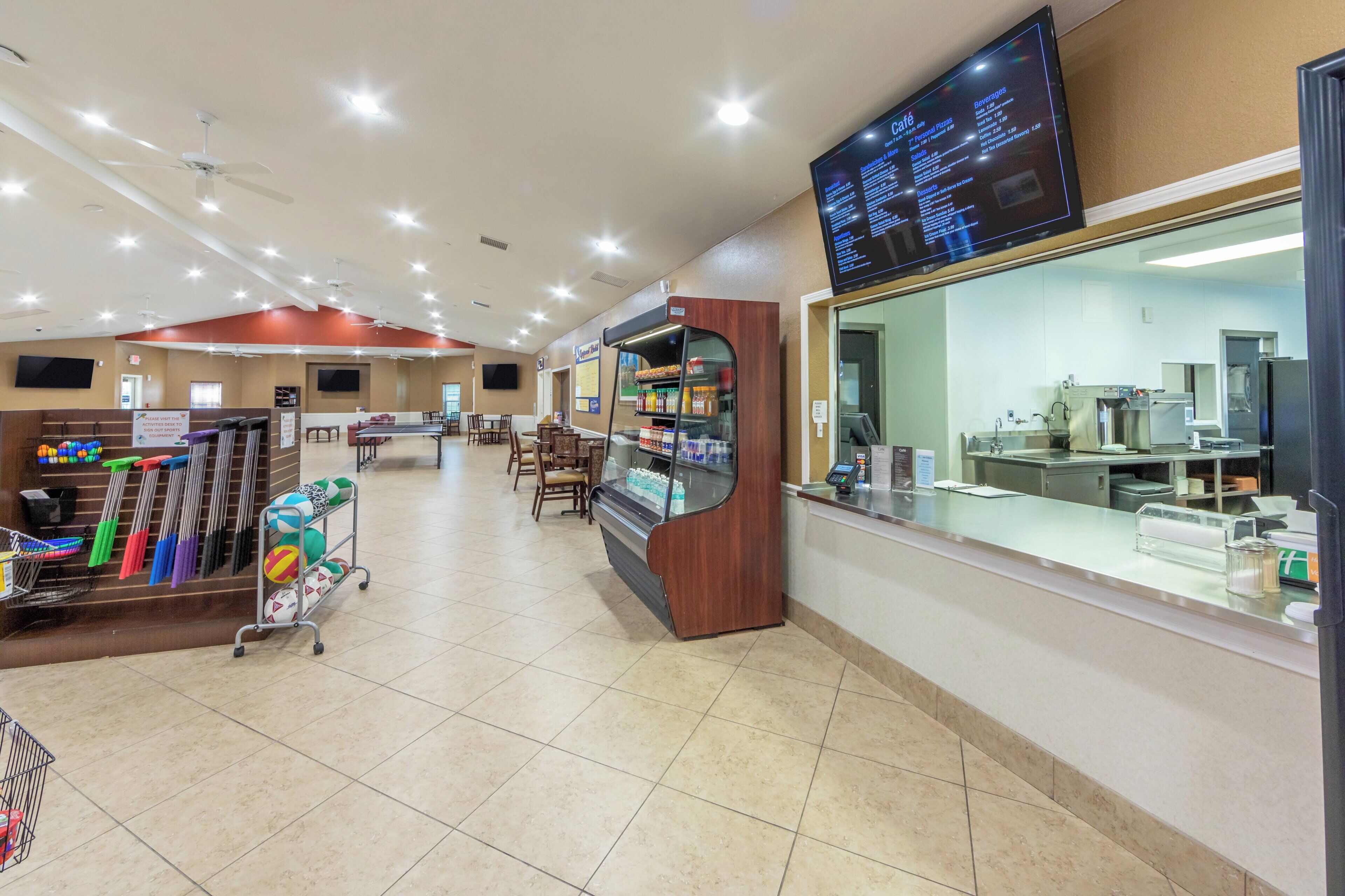 A cafe with a menu board, seating area, and a counter with a cash register.