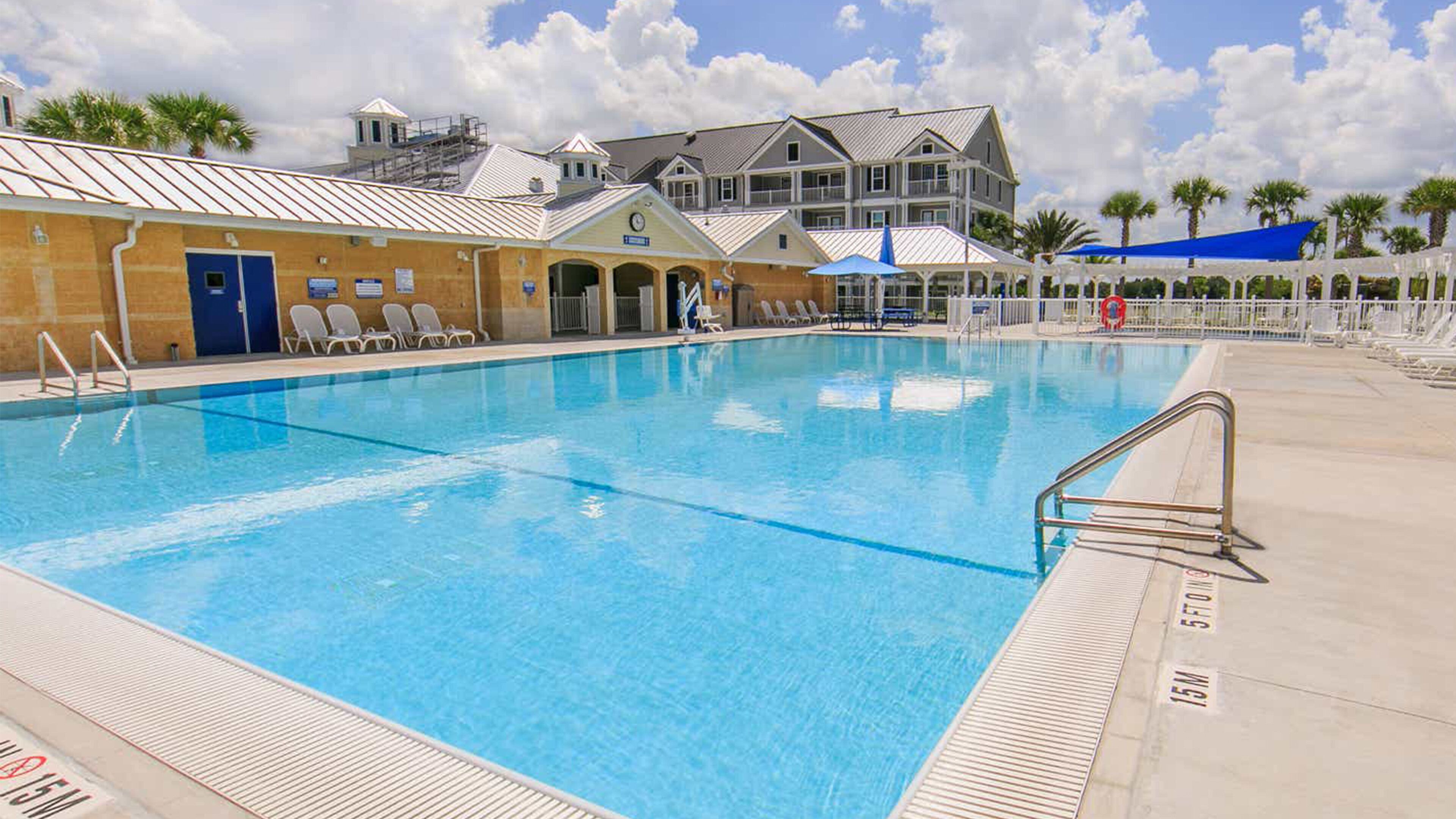 A swimming pool with a lifeguard tower, lounge chairs, and a covered area with umbrellas.