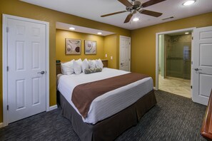 A hotel room with a large bed, a ceiling fan, and a shower area visible through an open door.