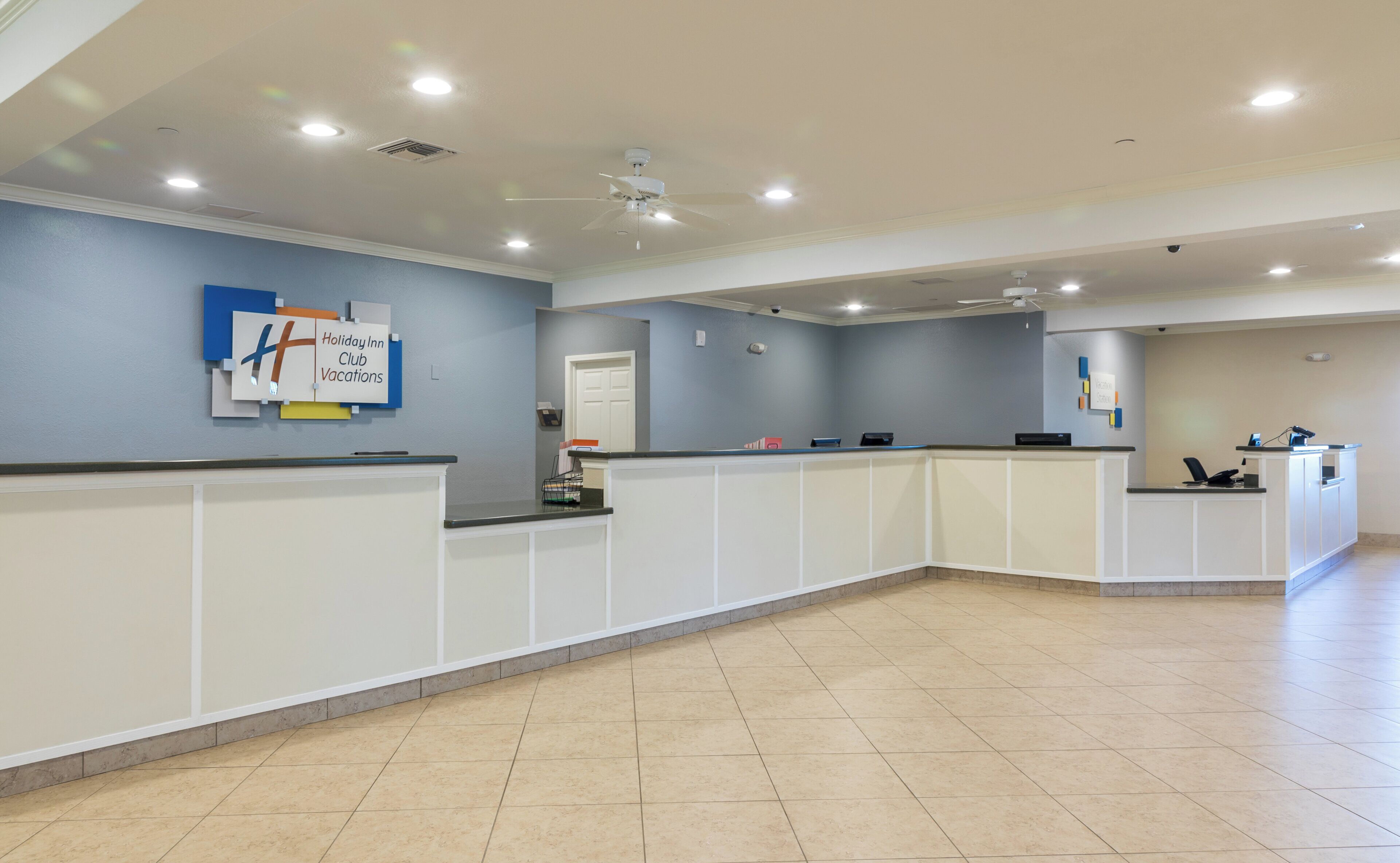 A reception area with a counter, a ceiling fan, and a sign indicating 'Holiday Inn Club Vacations'.