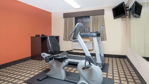 A fitness room with exercise equipment, a desk, and a television mounted on the wall. - Baymont by Wyndham Lakeville (Lakeville)