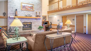 A spacious lobby with a brick fireplace, leather seating, and a balcony. - Baymont by Wyndham Lakeville (Lakeville)