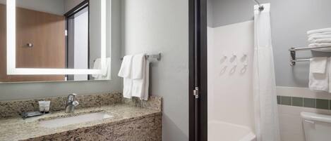 A bathroom with a granite countertop sink, a mirror, a shower with a glass door, and a toilet.