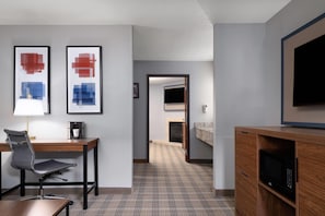 A hotel room with a desk, chair, coffee machine, television, and a microwave. - AmericInn by Wyndham Baldwin (Baldwin)