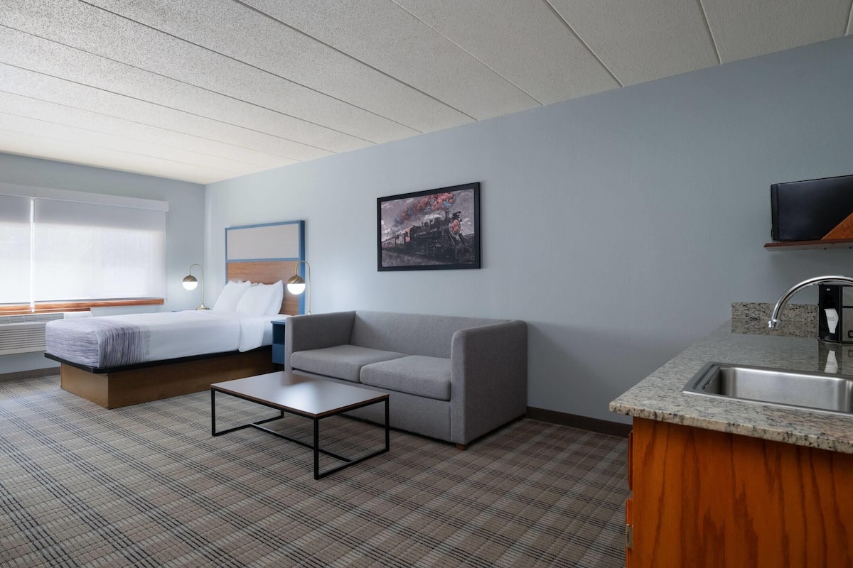 A hotel room with a bed, sofa, coffee table, and a kitchenette.