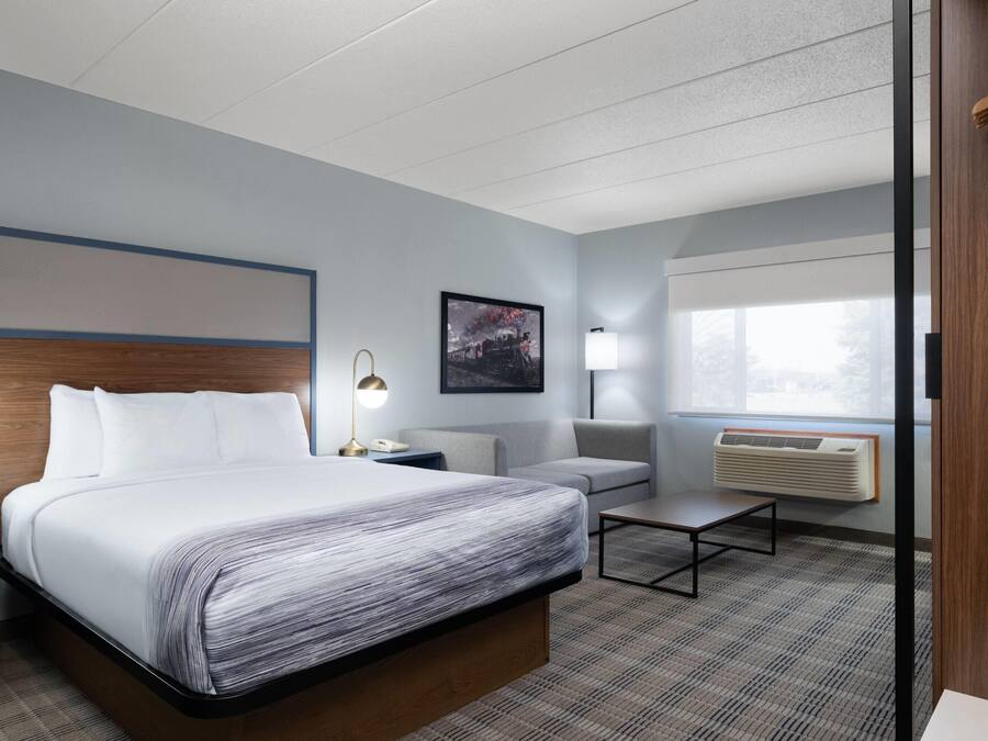 Ein Hotelzimmer mit Bett, Nachttischen, einer Sitzecke, einem Couchtisch, einer Wand-Klimaanlage und einem Fenster mit Blick.