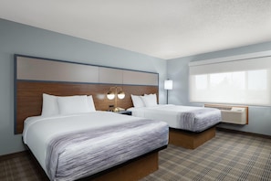 A hotel room with two beds, a large window, a wall-mounted air conditioner, and a headboard with built-in lighting. - AmericInn by Wyndham Baldwin (Baldwin)