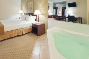 Une chambre d’hôtel avec un lit, une table de chevet, une lampe et une grande baignoire.
