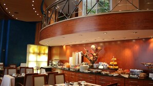 A hotel dining area with a buffet setup, wooden paneling, and a glass railing overlooking the interior. - Hotel Garbi Millenni (Barcelona)
