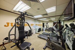 A gym with exercise equipment, a water dispenser, and a mirror on the wall.