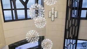 A lobby with a modern chandelier, a fireplace, and a large window with a view of the city. - Rosedale Hotel Hong Kong (Hong Kong)