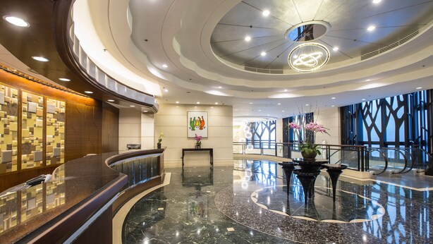 A modern hotel lobby with a curved reception desk, a marble floor, and a large chandelier. - Rosedale Hotel Hong Kong (Hong Kong)