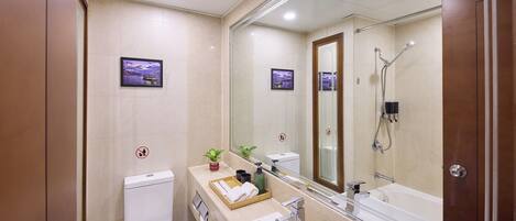 A modern bathroom with a toilet, sink, and shower. There are framed pictures on the wall and a small plant on the counter.