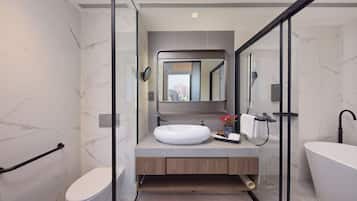 A modern bathroom with a glass-enclosed shower, a white toilet, a wooden vanity with a sink, and a freestanding bathtub.