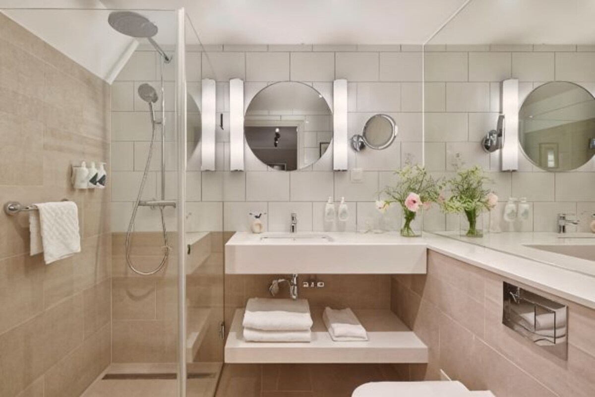 A modern bathroom with a glass shower enclosure, a vanity with a sink, and two mirrors.