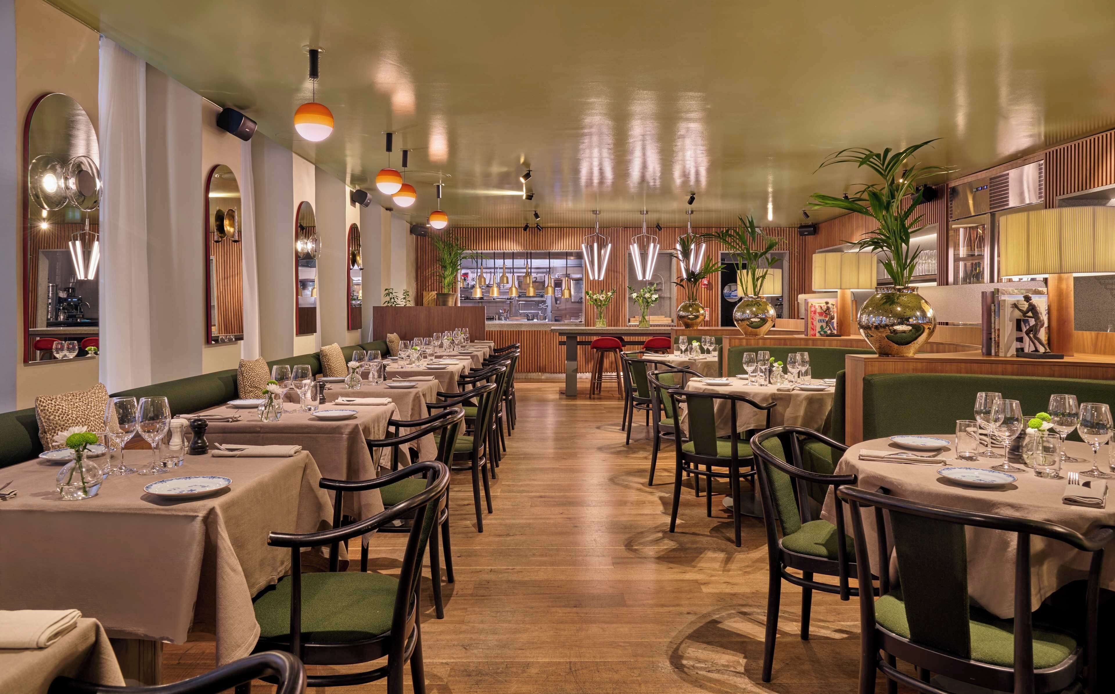 Un restaurant doté de nombreuses tables dressées pour le service, avec une variété de chaises et un plancher en bois.